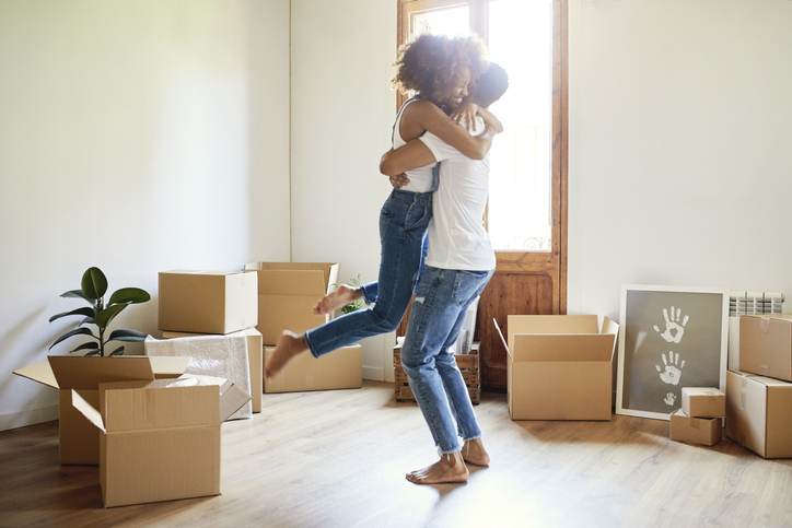 Young man lifting woman in new house