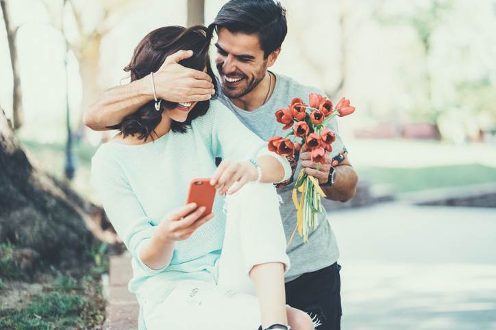 Young man surprising his girlfriend with bouquet of tulips