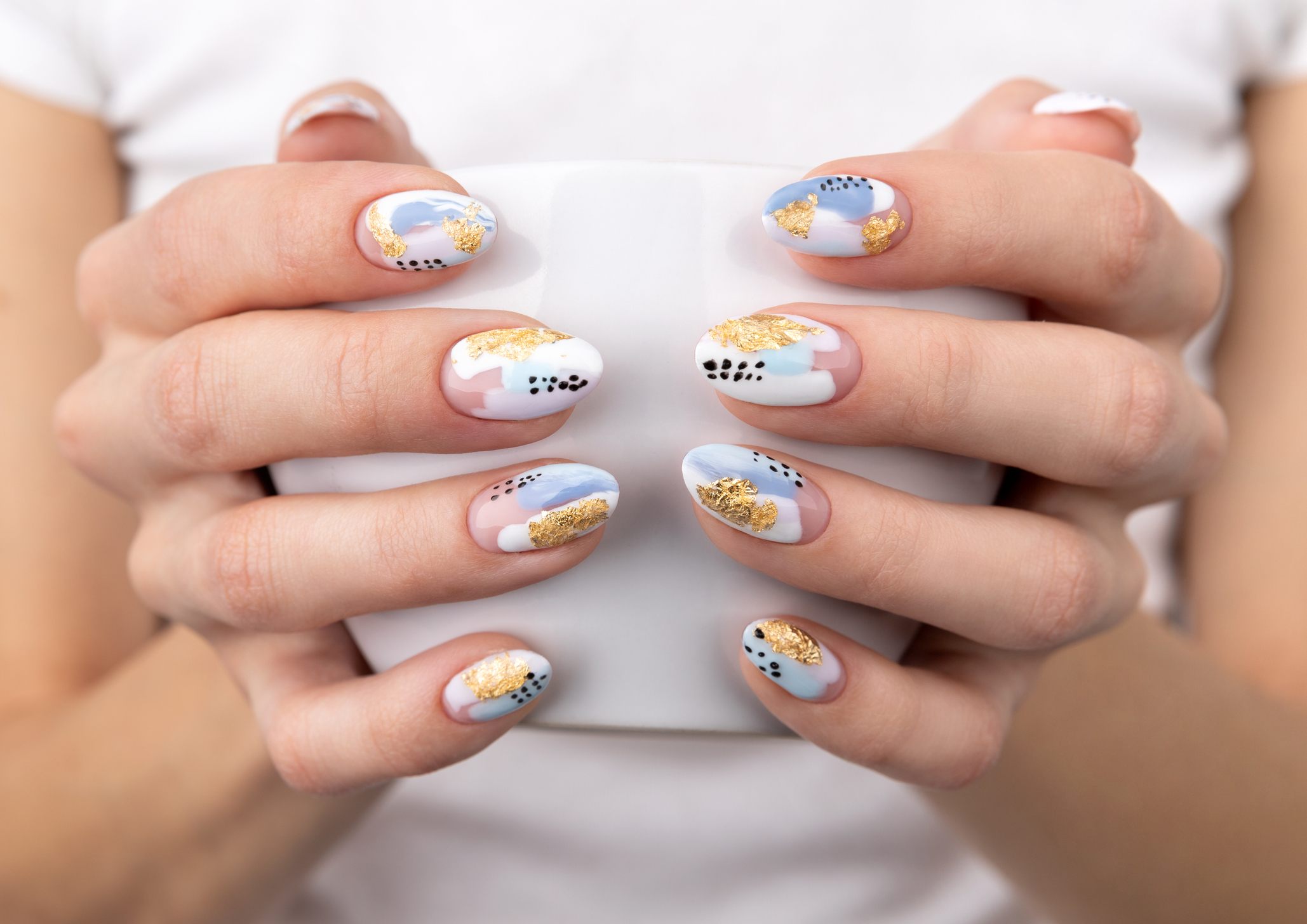 Woman's hands with trendy pastel color nails holding cup