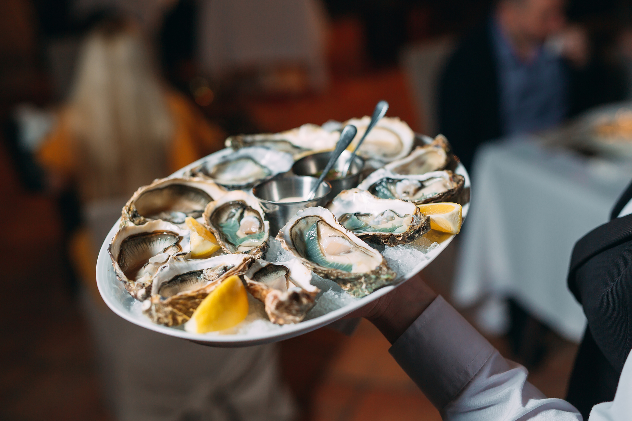 a waiter holds a serving of oysters in a restaurant.