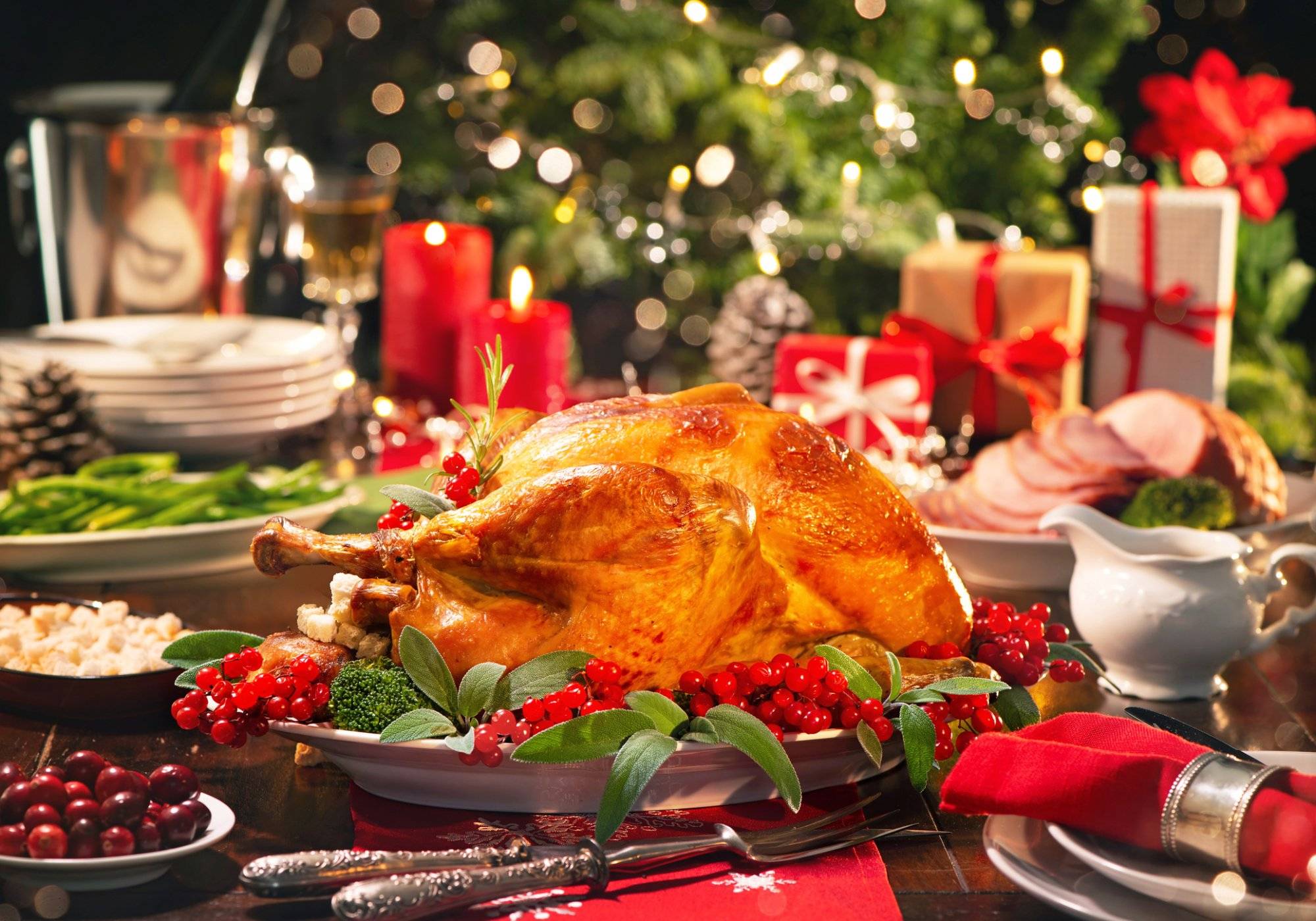 Christmas turkey dinner Christmas turkey dinner. Baked turkey garnished with red berries and sage leaves in front of Christmas tree and burning candles